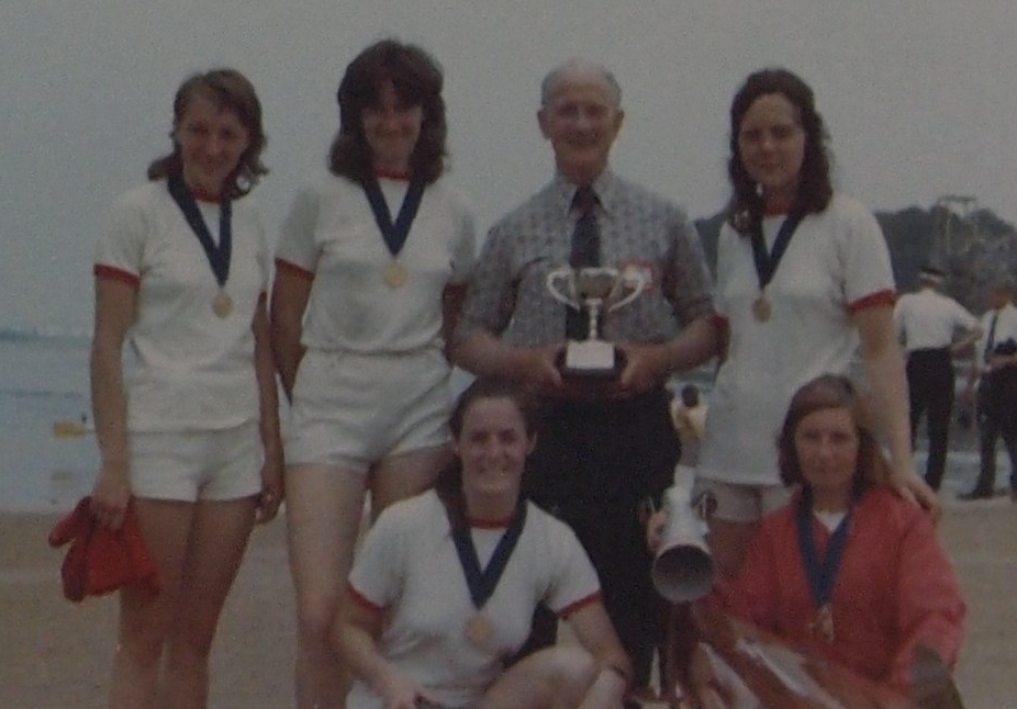 5 women wearing medals with coach 