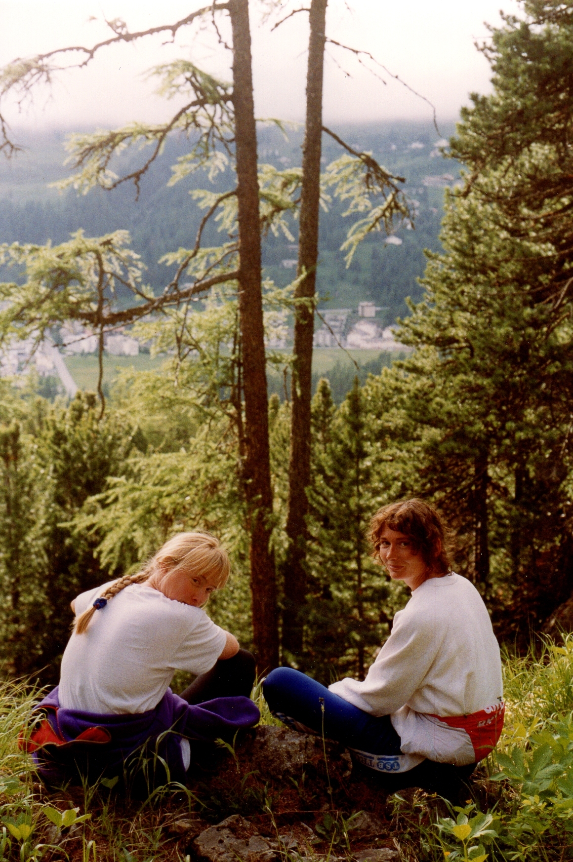 Two women in forest above lake