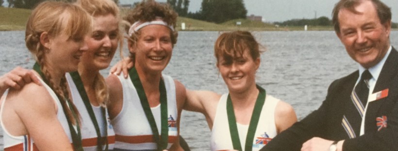 4 women being presented with pennant by man in blazer