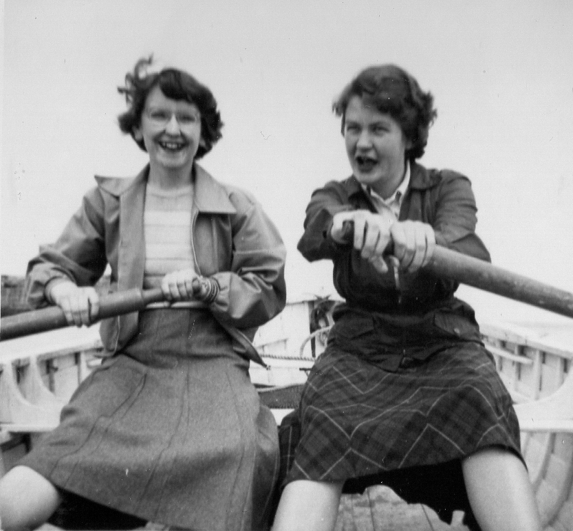 Two in women skirts rowing in dinghy laughig