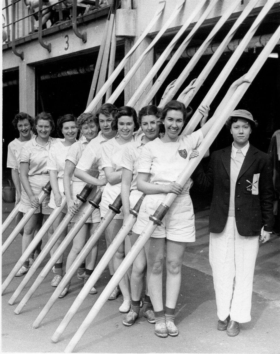 Women in front of boathouse with oars