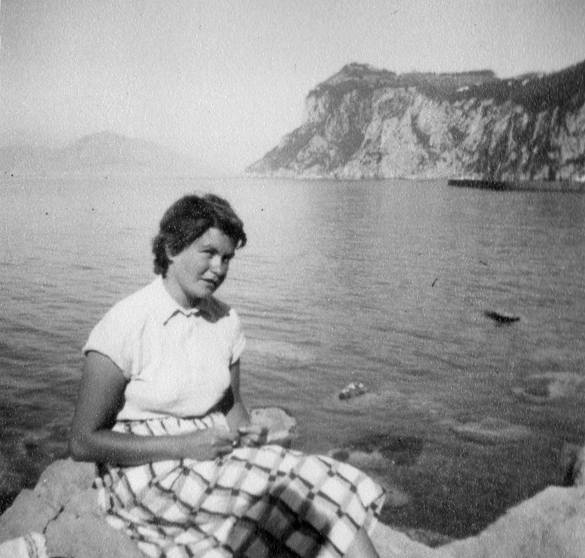 Woman sitting on rock by coastal bay