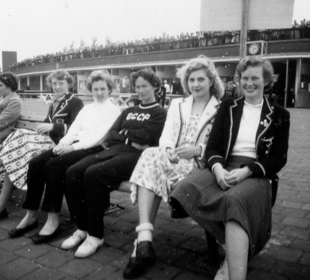 Five women sitting on bench - 3 in rowing blazers