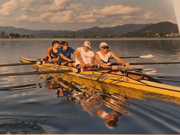 Women's four in yellow boat on glassy lake