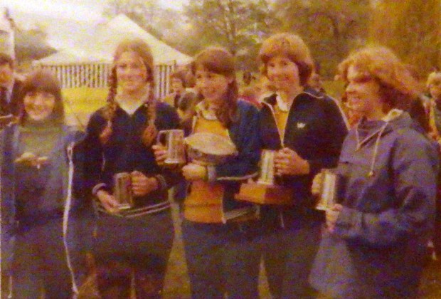 four girls with trophies and marquee in background