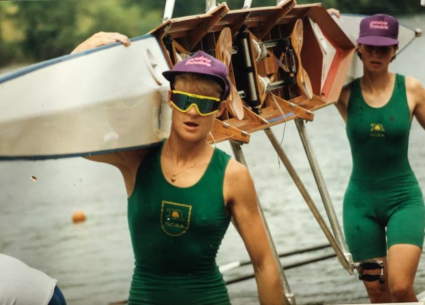 Two wome in green kit carrying boat