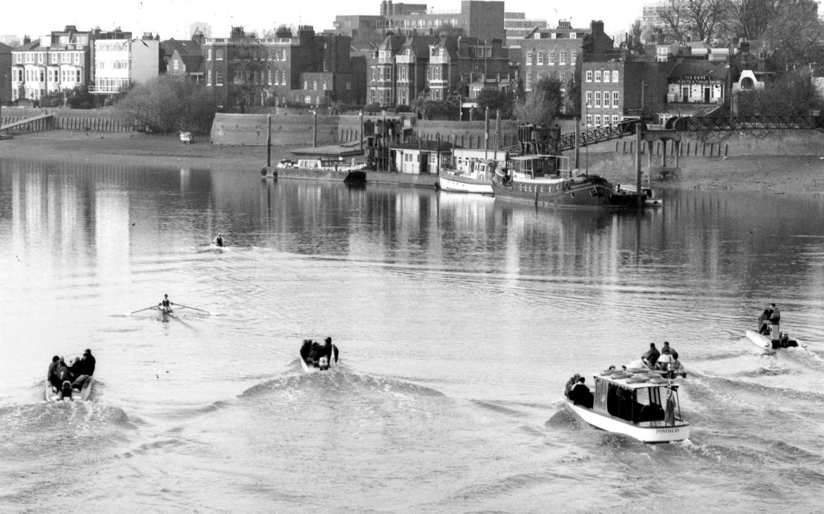 b/w photo of 2 scullers passing Dove Pier pursued by 5 launches