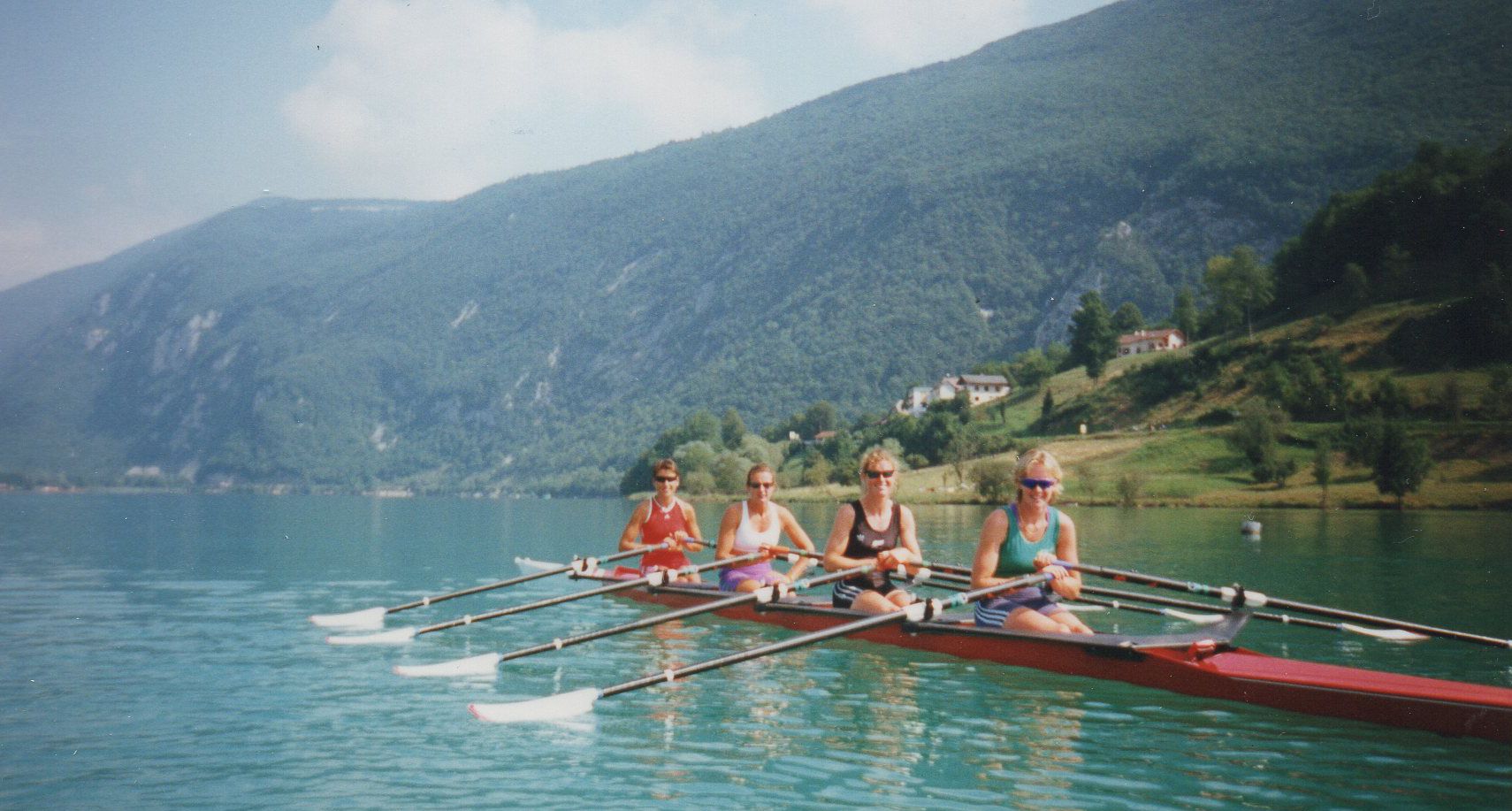 women in red boat on lake with beautiful mountains in background
