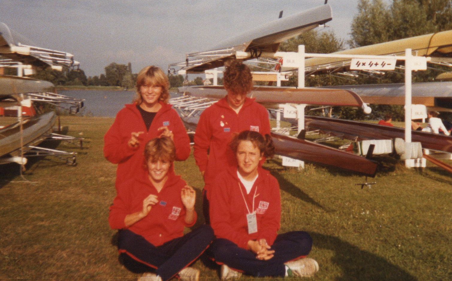 4 girls in red track suit tops by boat racks