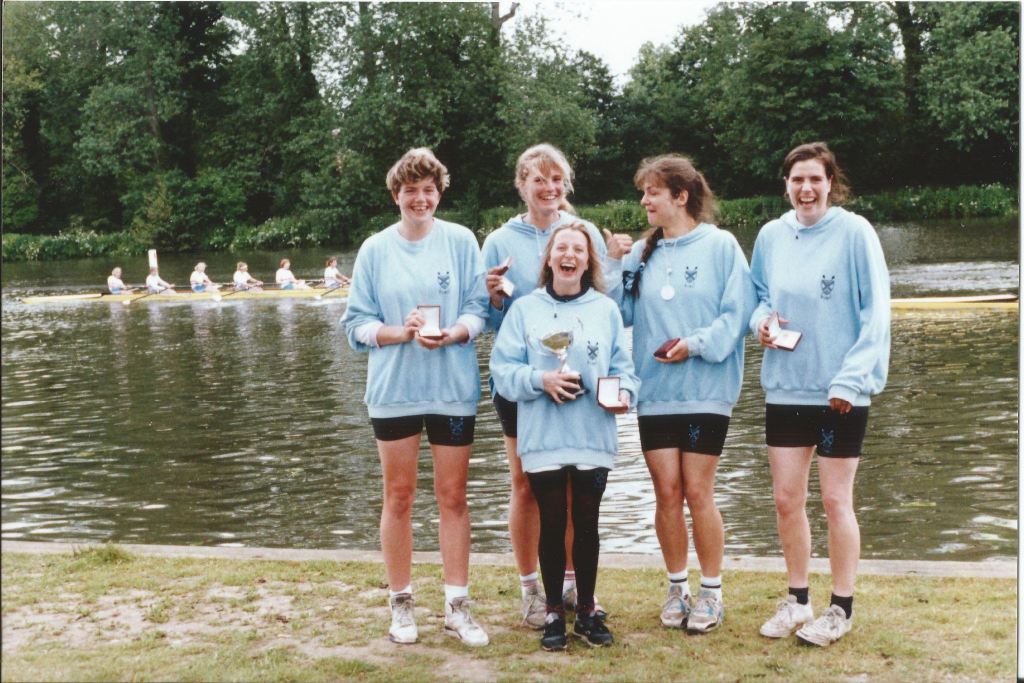 5 women in pale blue hoodies with medals by river in Henley