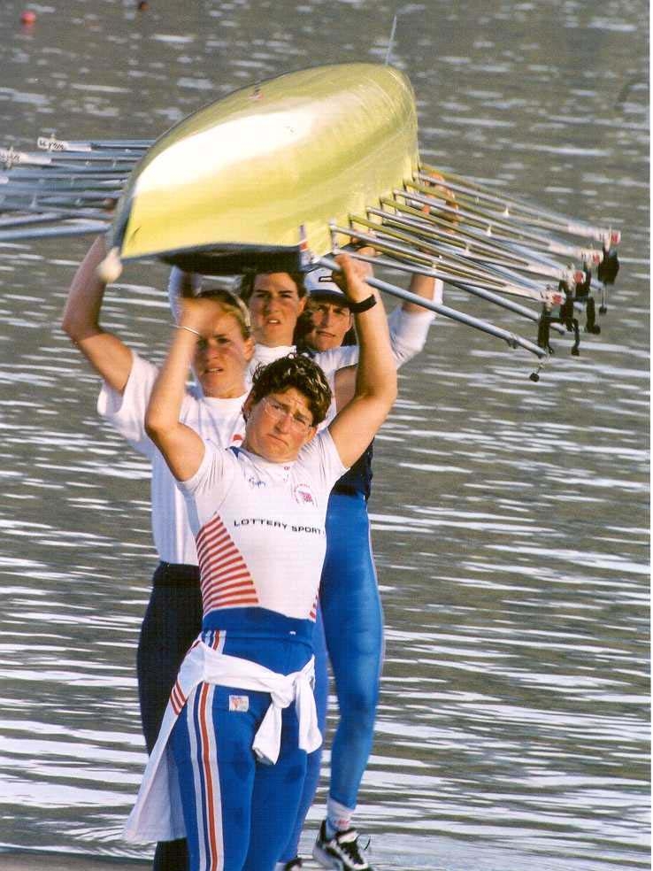 4 women with yellow boat over heads