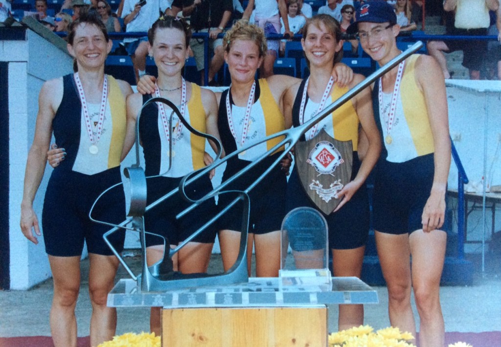 5 women with medals and oar-shaped trophy