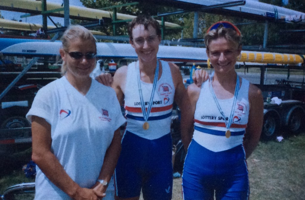 3women by boat trailer, 2 with medals
