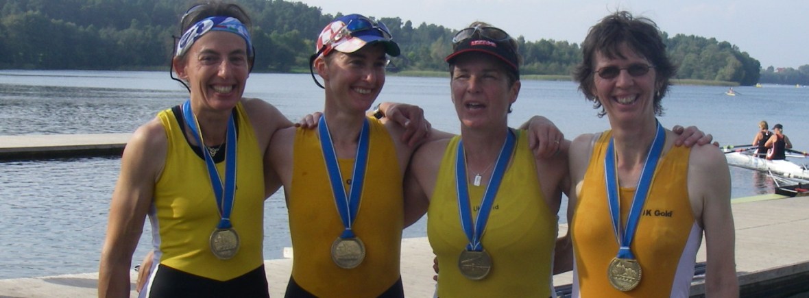 4 women in gold racing vests with medals