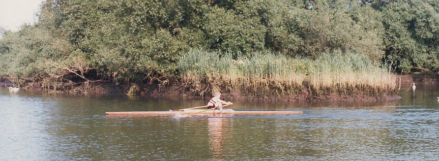 Woman sculling in wooden boat
