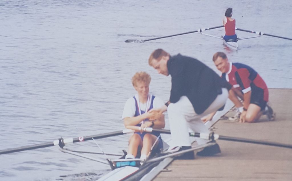 Woman in sculling boat breing presented iwth medal