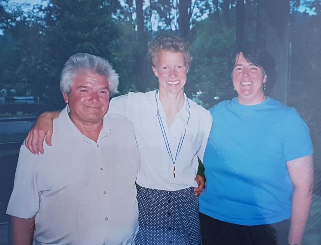 woman rowerwearing gold medal with 2 coaches