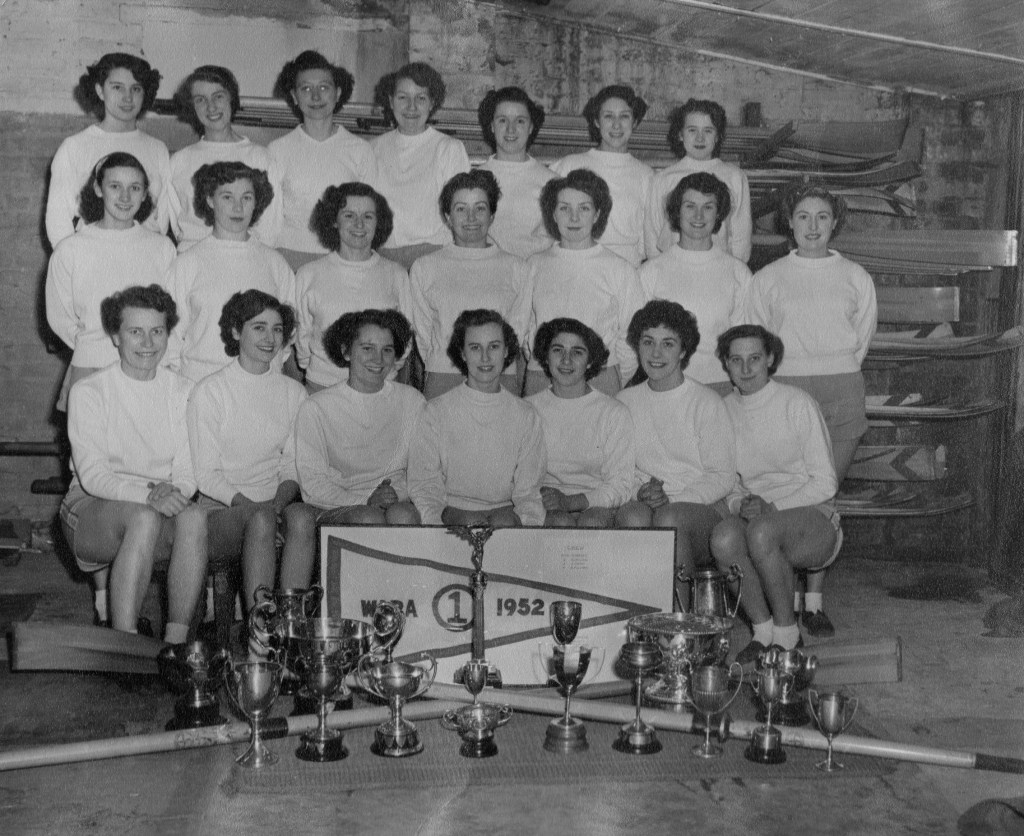 Group of women in white tops with a collettion of trophies